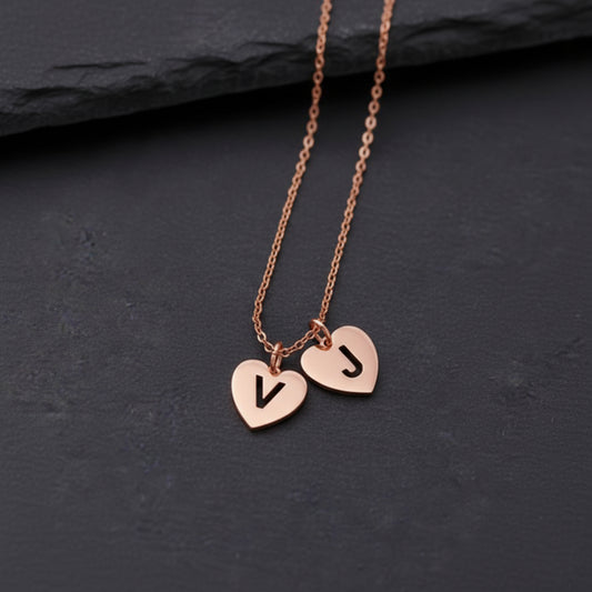 Rose gold necklace with heart-shaped pendants on a dark surface