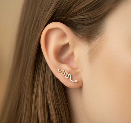 Close-up of an ear wearing a gold snake shaped earring