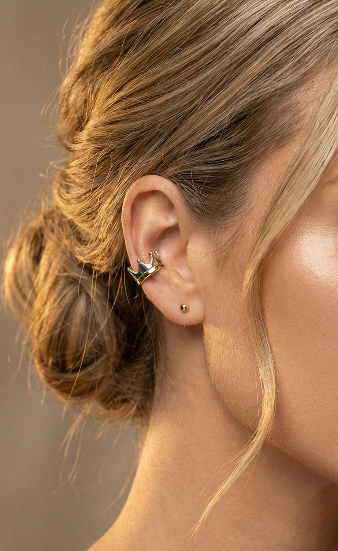 Close-up of a person wearing gold earrings with a blurred background