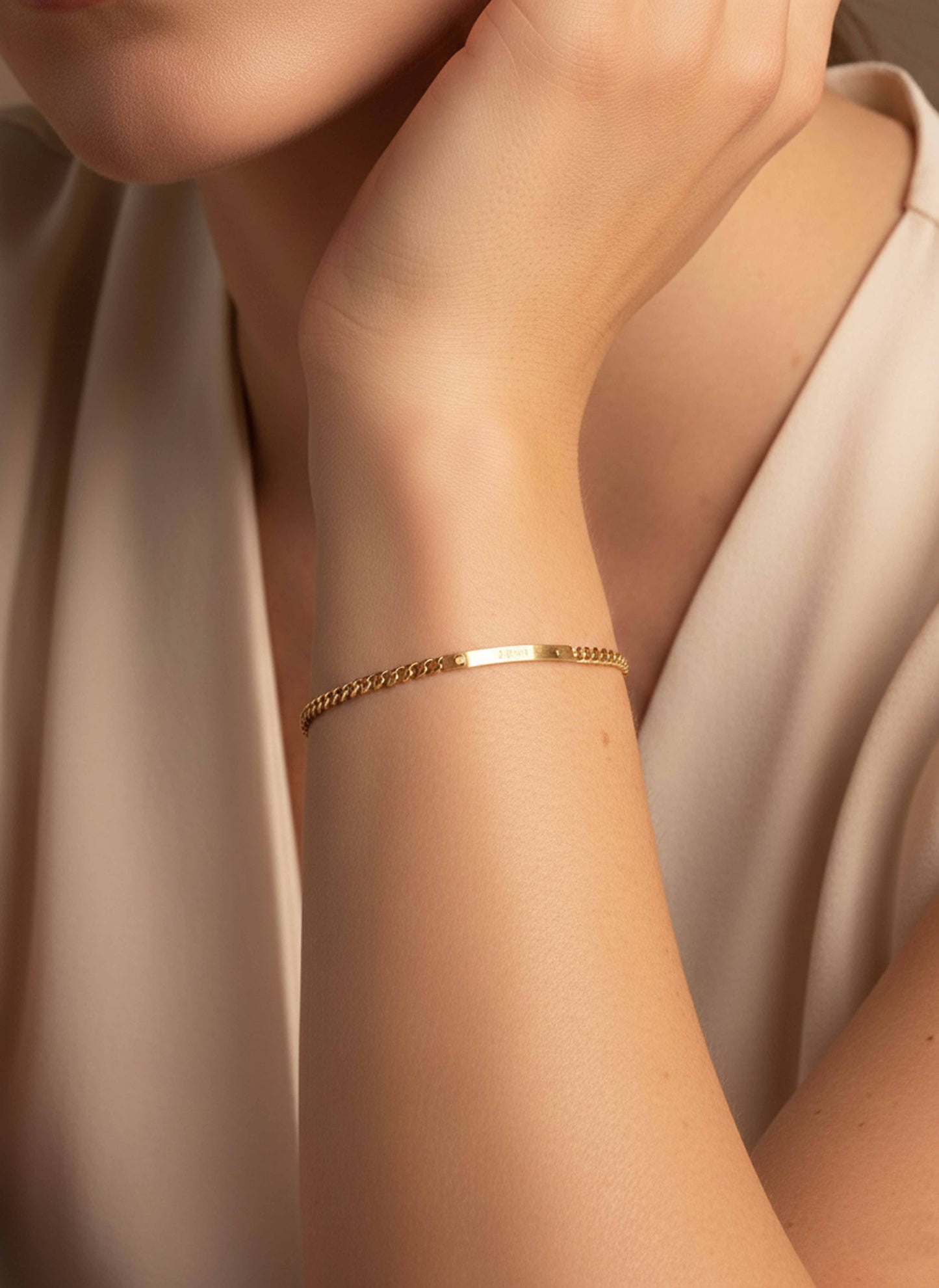 Gold bracelet on a person's wrist with a neutral background