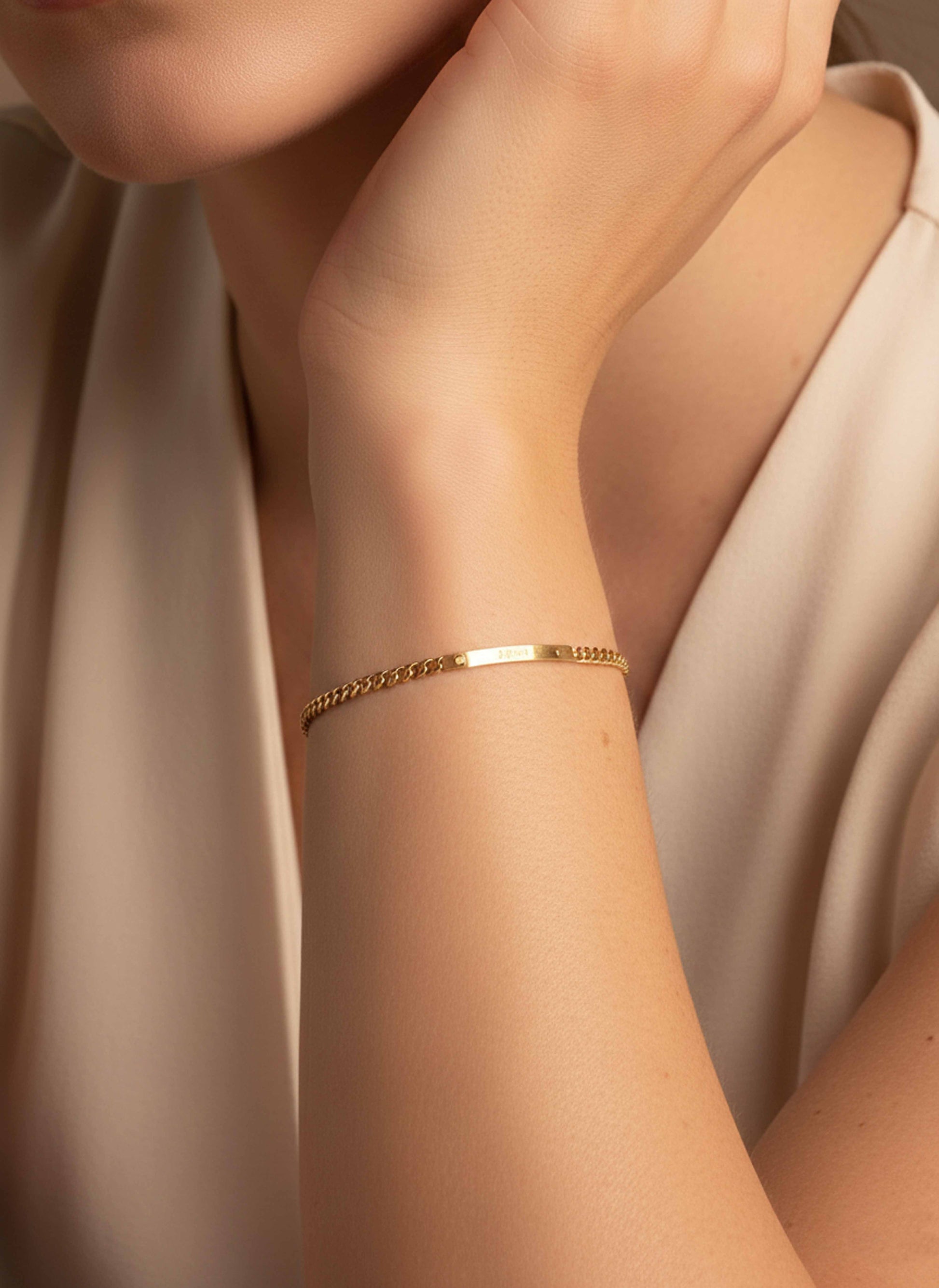 Gold bracelet on a person's wrist with a neutral background