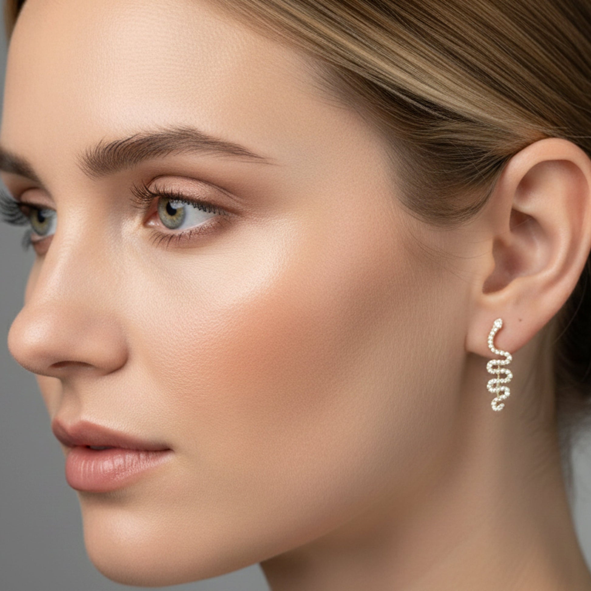Close-up of a woman wearing a delicate earring against a neutral background