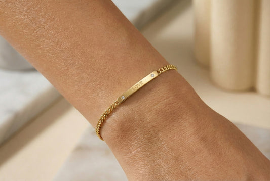 Gold bracelet on a person's wrist with a neutral background