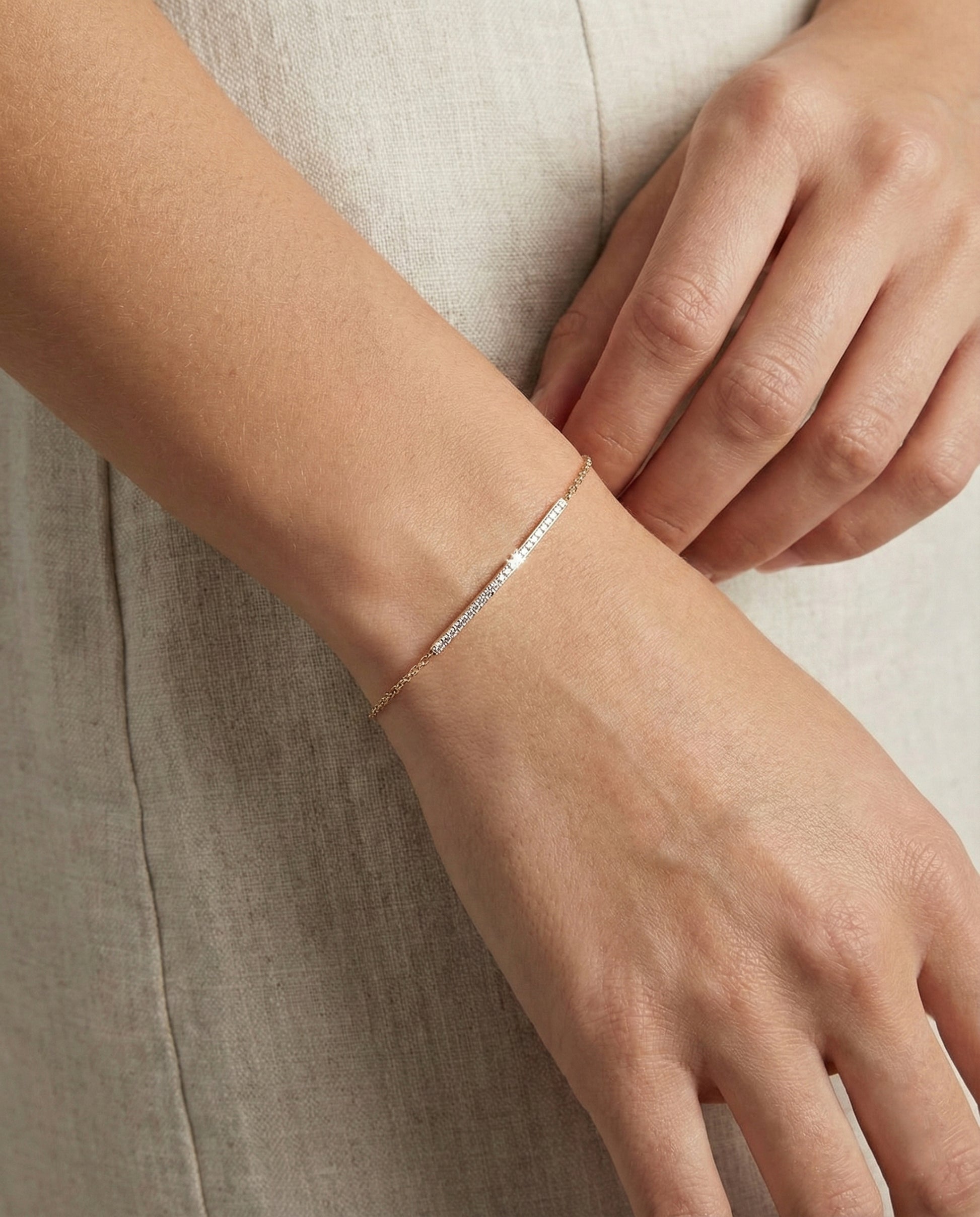 Close-up of a hand wearing a delicate  bracelet on a neutral background