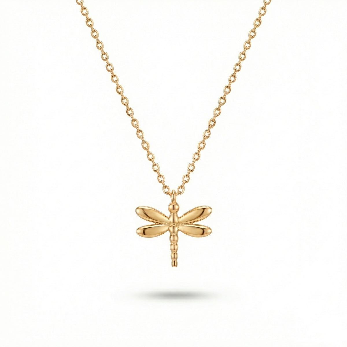 A delicate gold chain necklace featuring a polished dragonfly pendant, displayed against a clean white background with a soft shadow beneath.