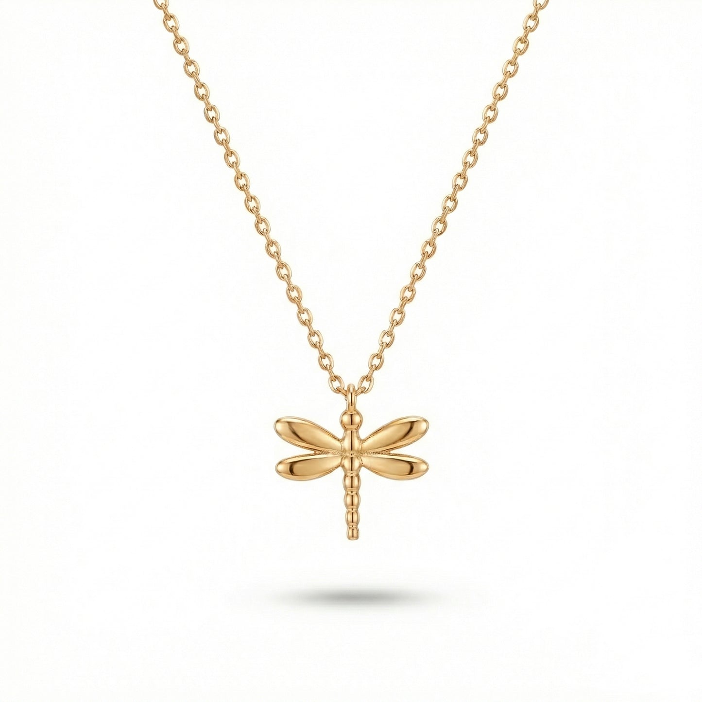 Gold dragonfly necklace on a white background