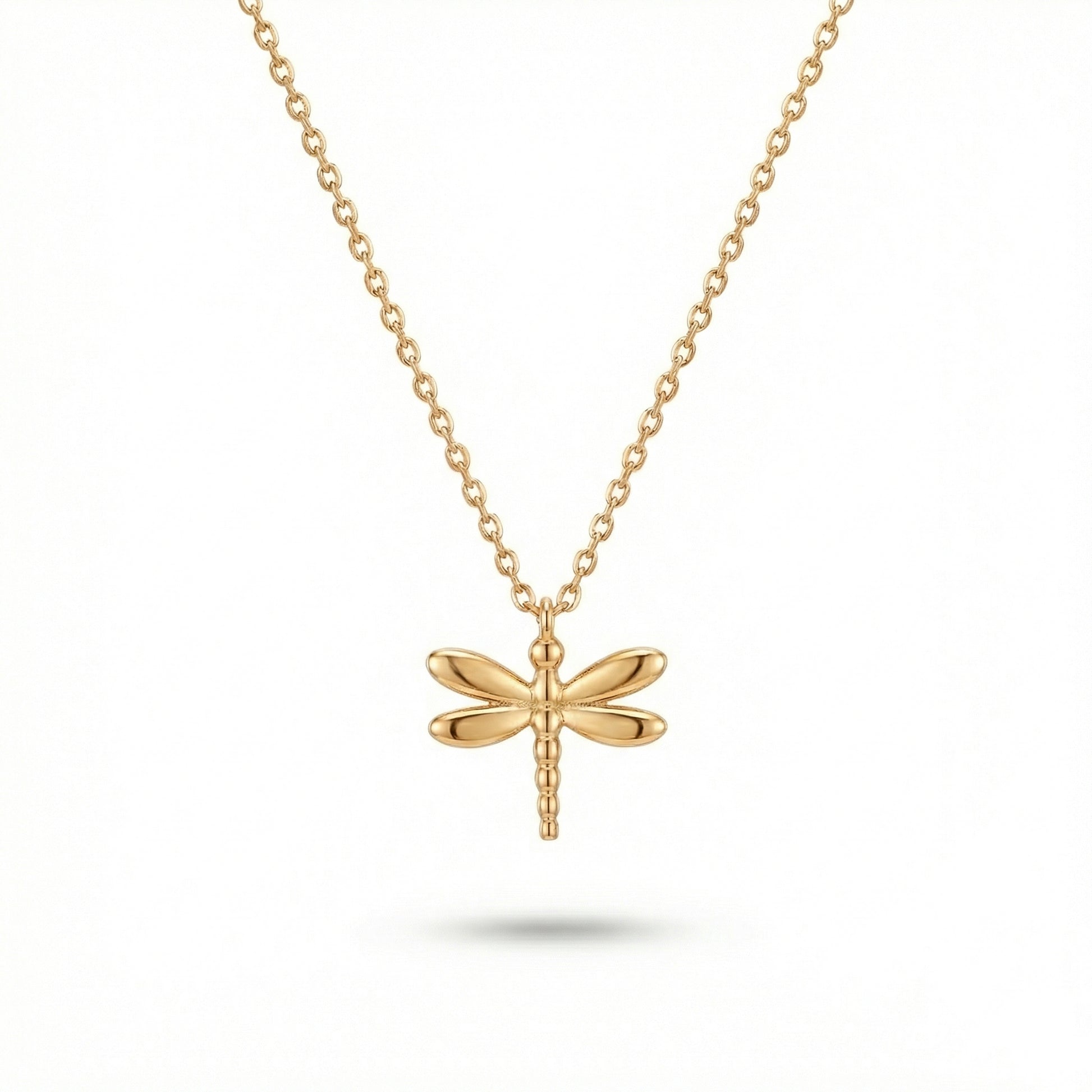 Gold dragonfly necklace on a white background