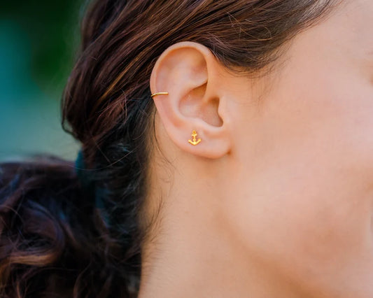 Close-up of an ear with gold  anchor earrings