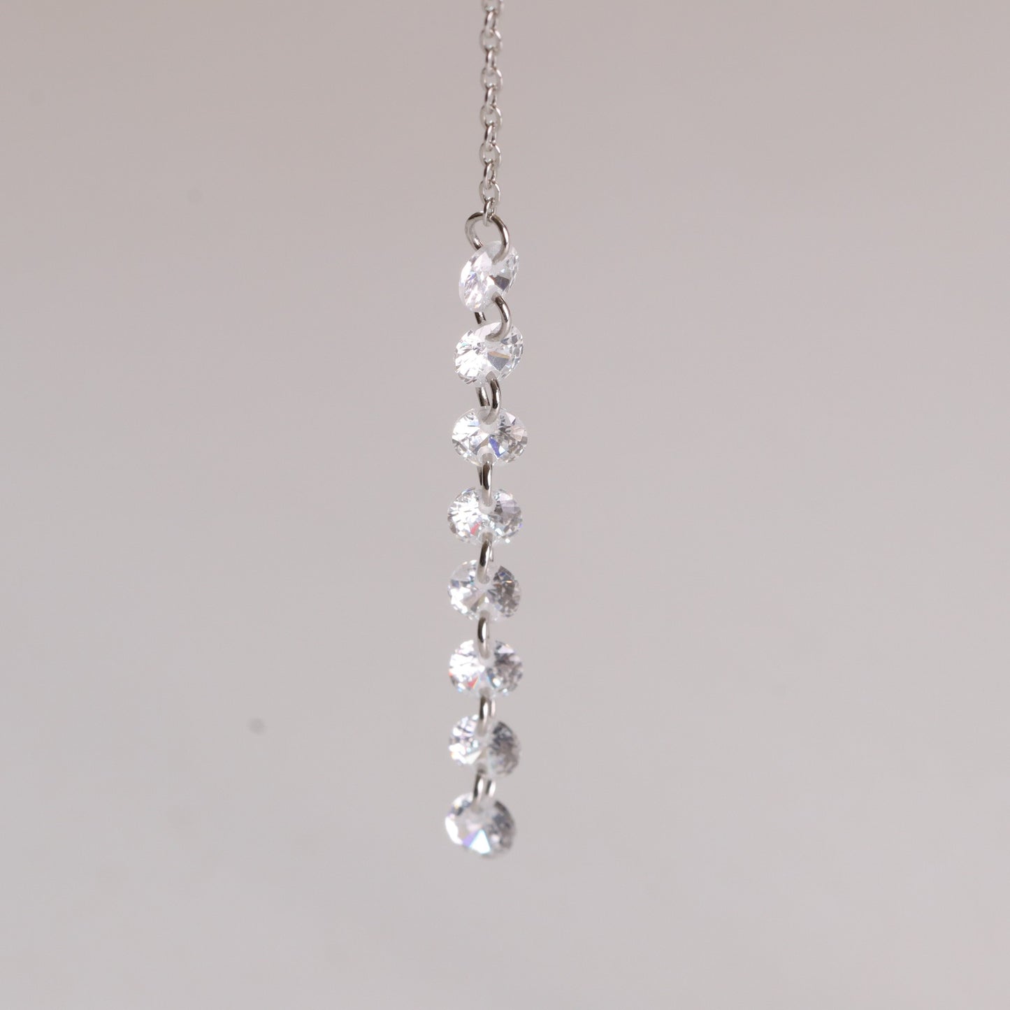 Silver necklace with clear gemstones on a light gray background