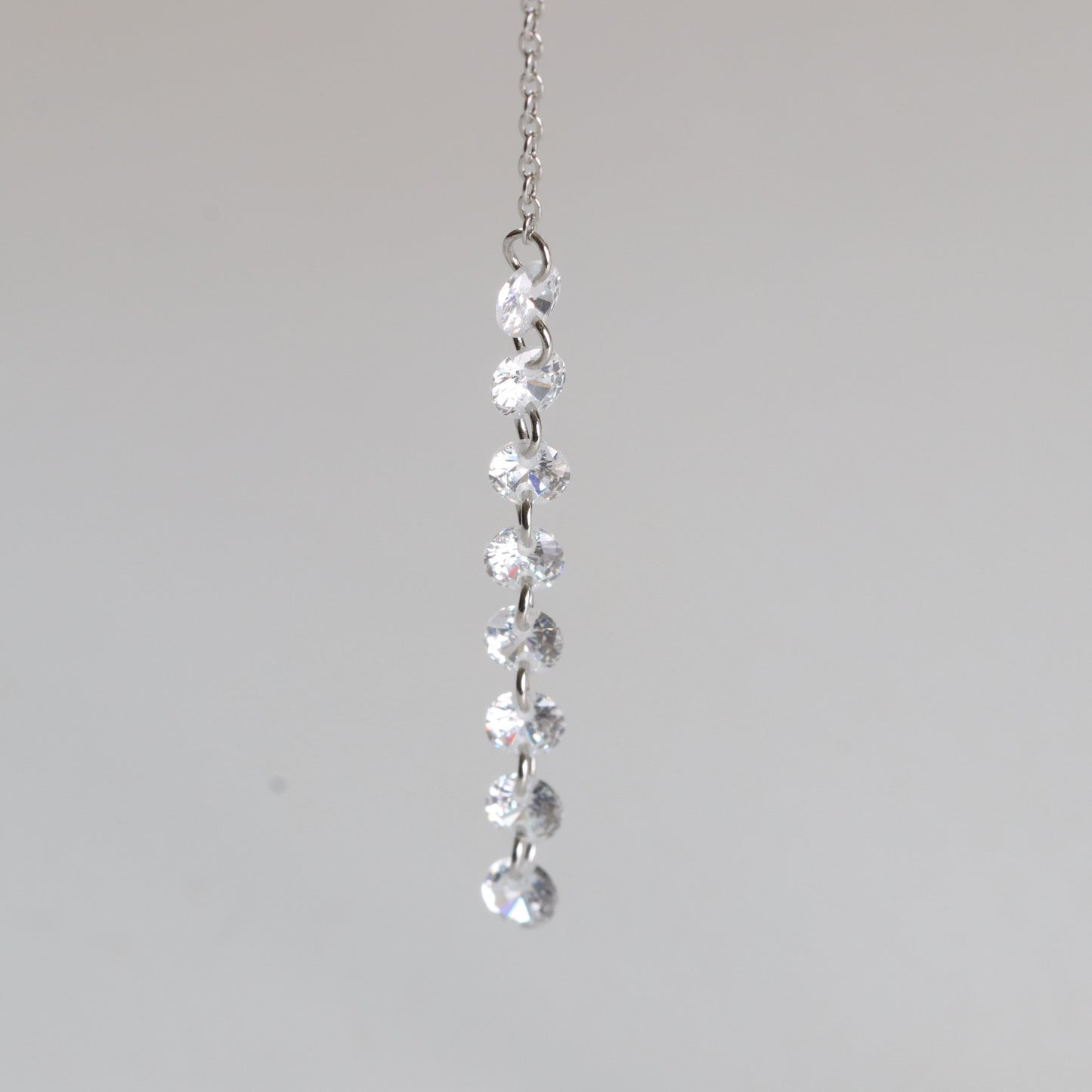 Silver necklace with clear gemstones on a light gray background
