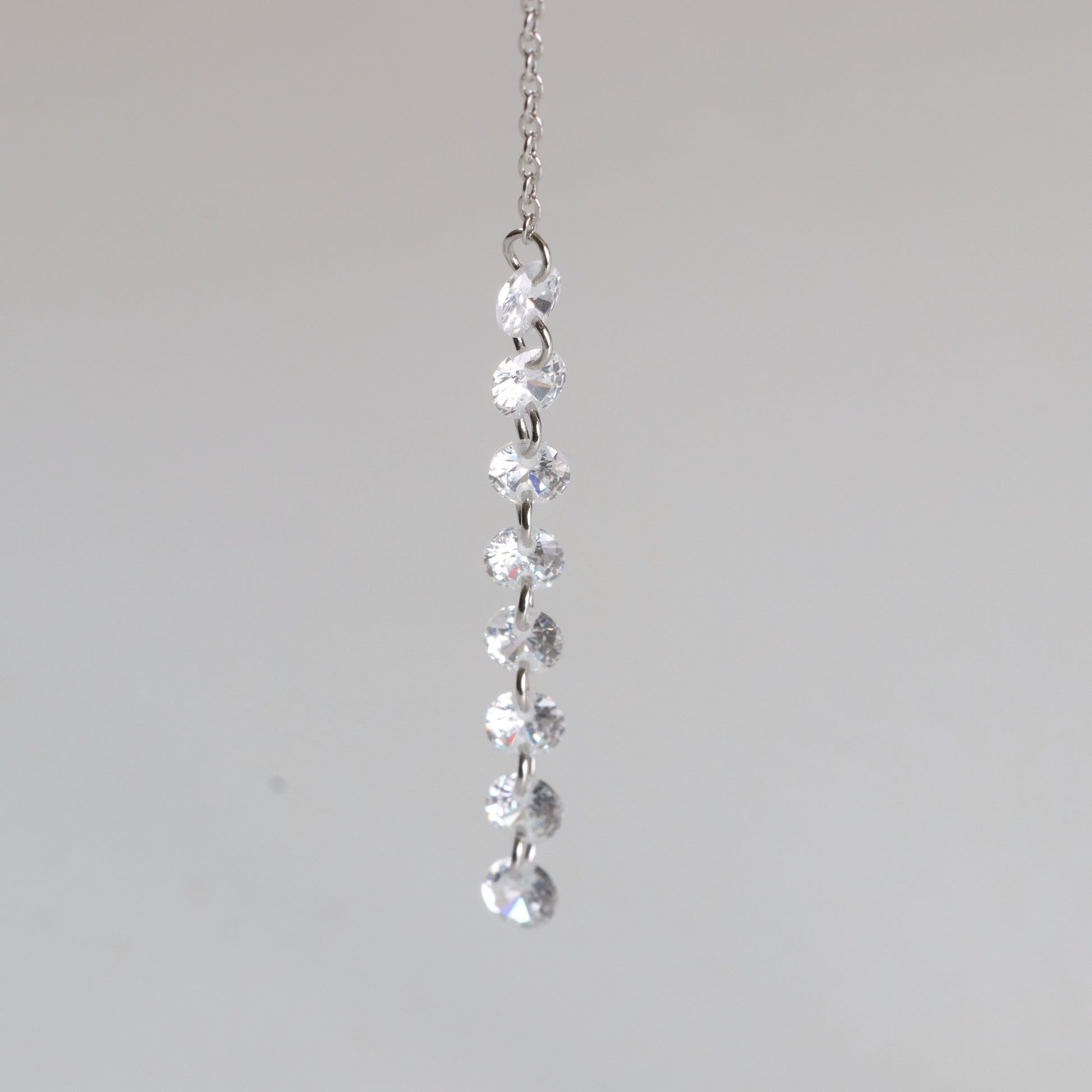 Silver necklace with clear gemstones on a light gray background