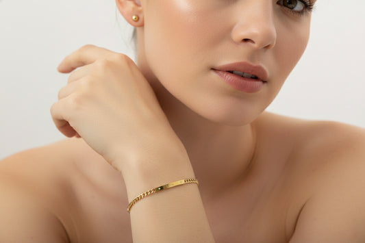 Woman wearing a gold bracelet on a plain background