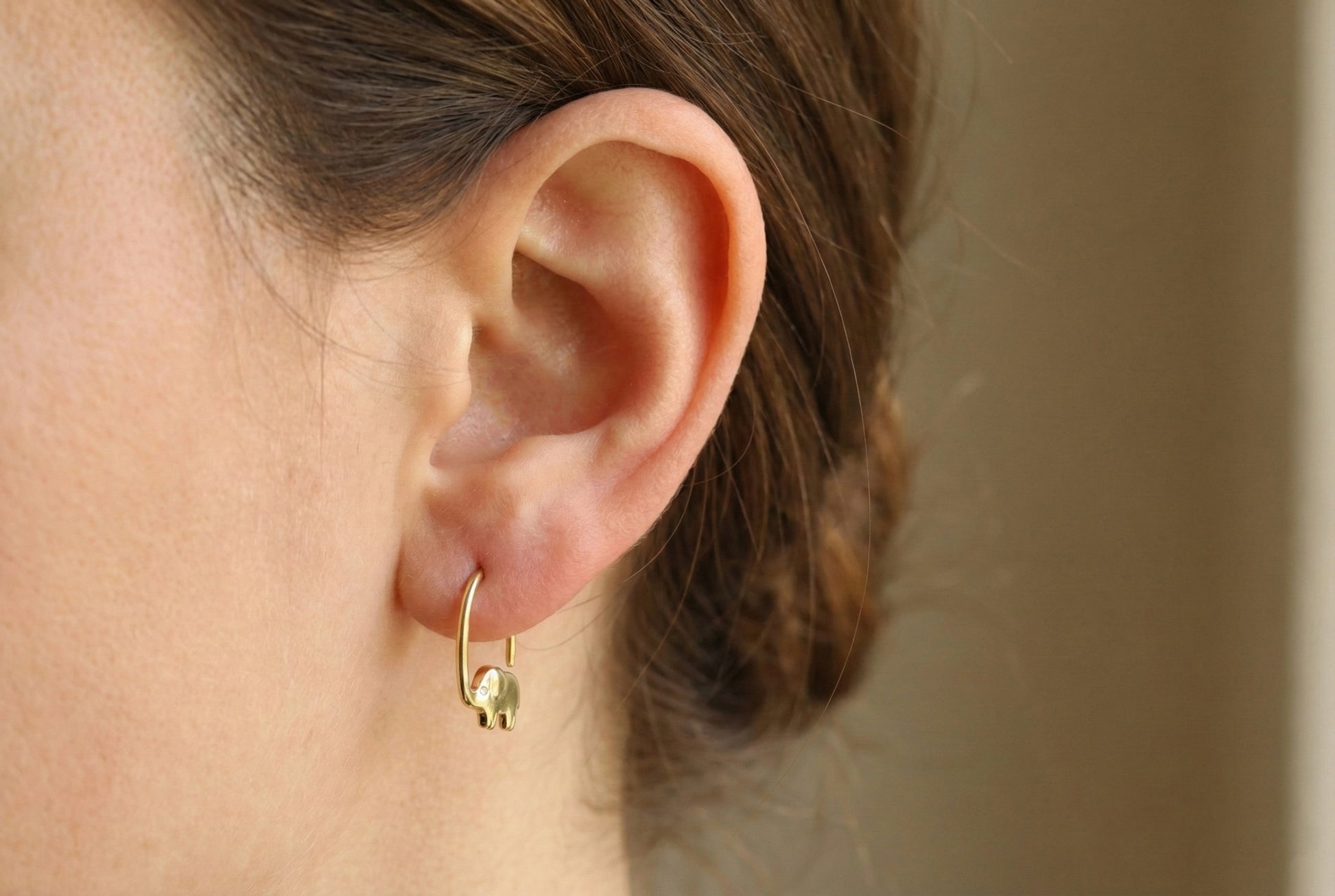 Close-up of a person wearing a gold hoop earring with a blurred background