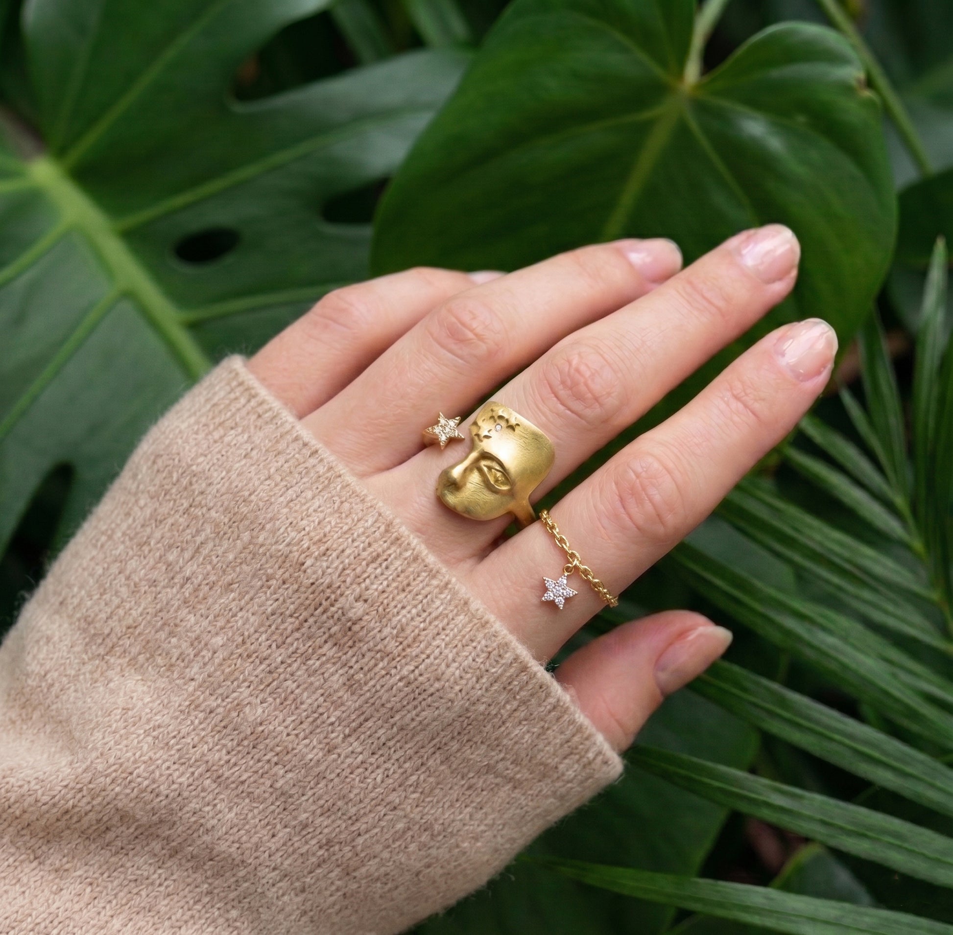 gold ring face on hand with green jungle background
