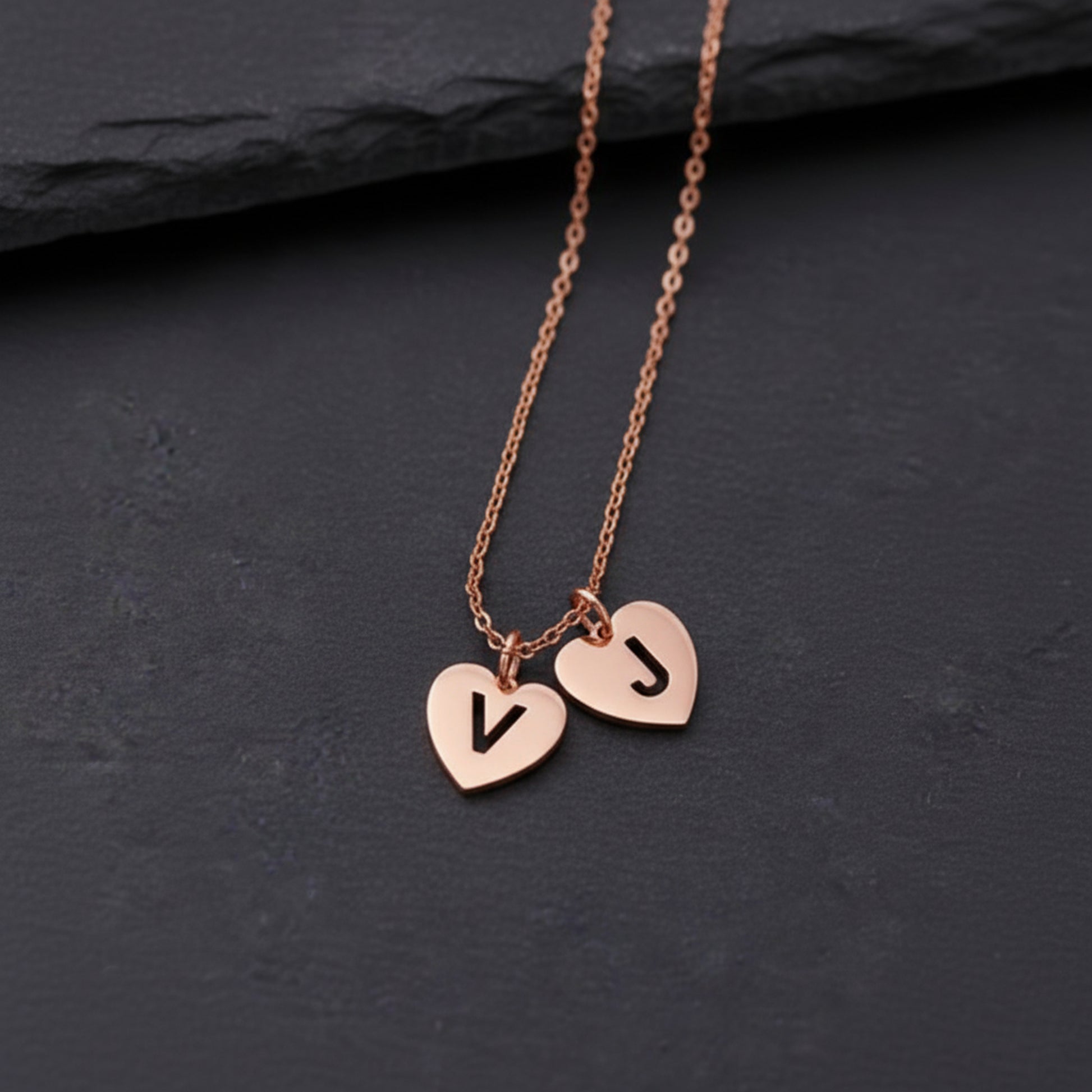 Rose gold necklace with heart-shaped pendants on a dark surface