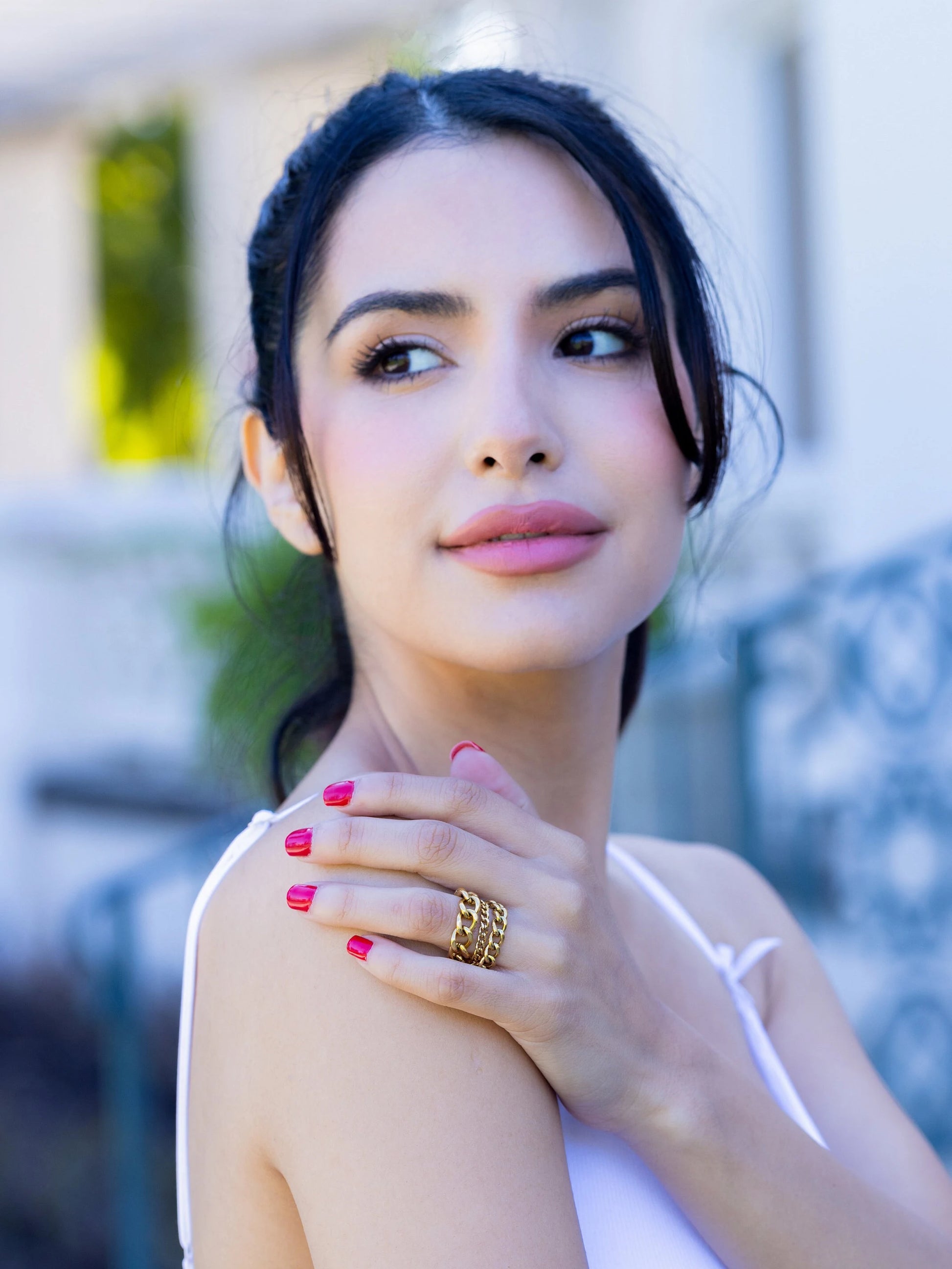 Woman wearing gold rings on a blurred outdoor background