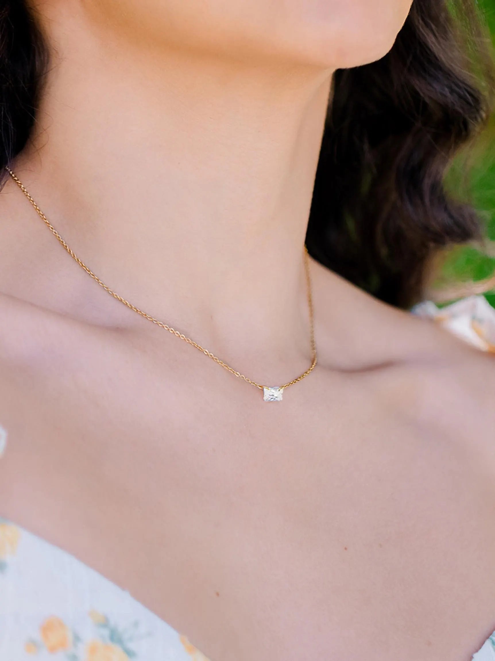 woman with  warring an emerald cut zircon with a gold chain