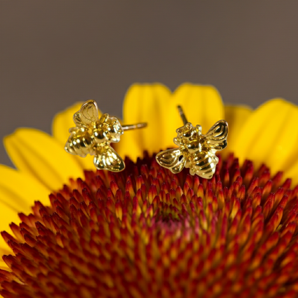 Gold bee earrings on a yellow flower with a brown background