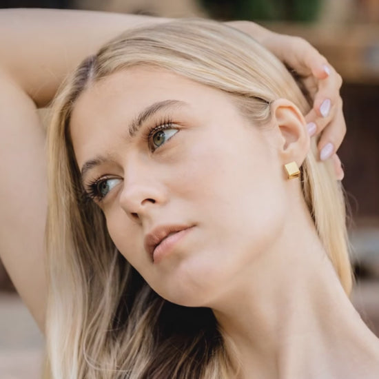 square gold earrings on a blond woman