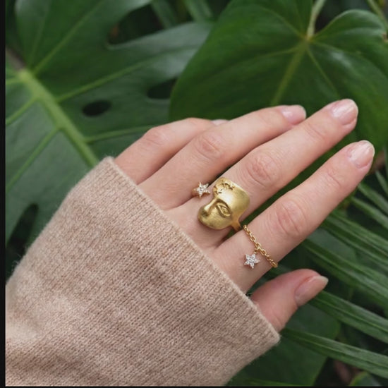 gold face ring on a hand with a jungle background