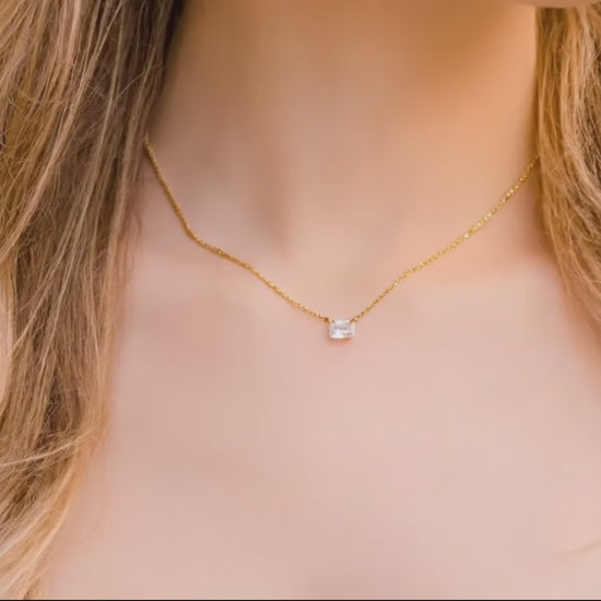 woman with long blond hair warring an emerald cut zircon with a gold chain