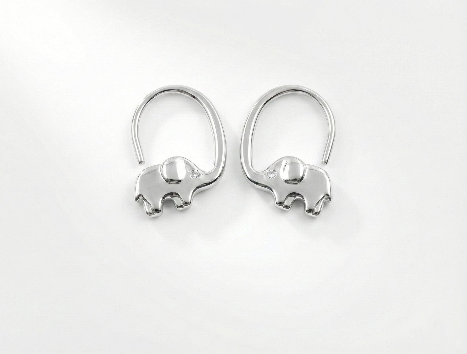 Pair of silver elephant-shaped earrings on a white background