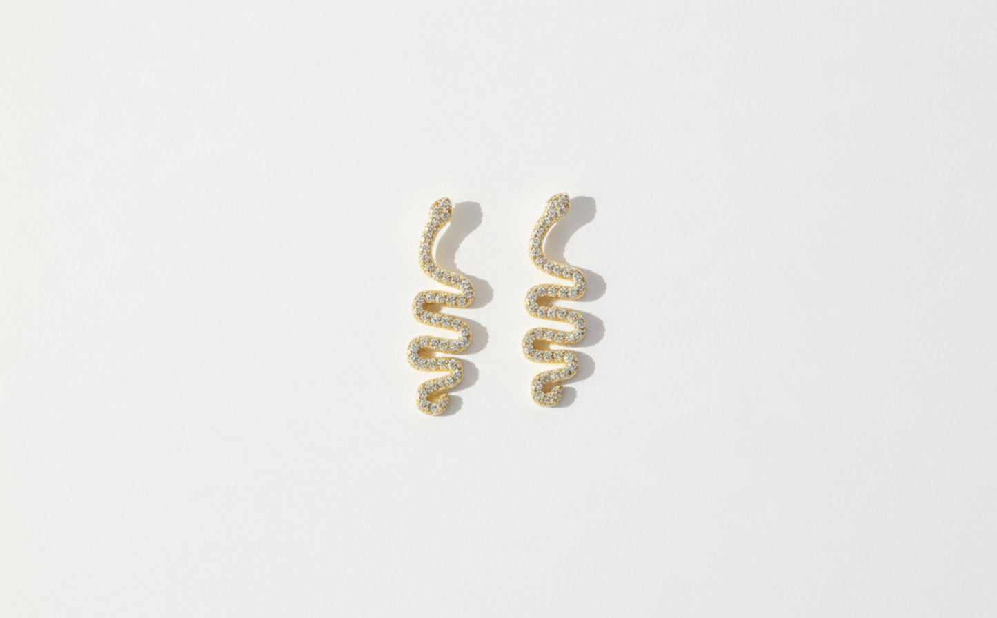 Pair of gold spiral earrings on a light gray background