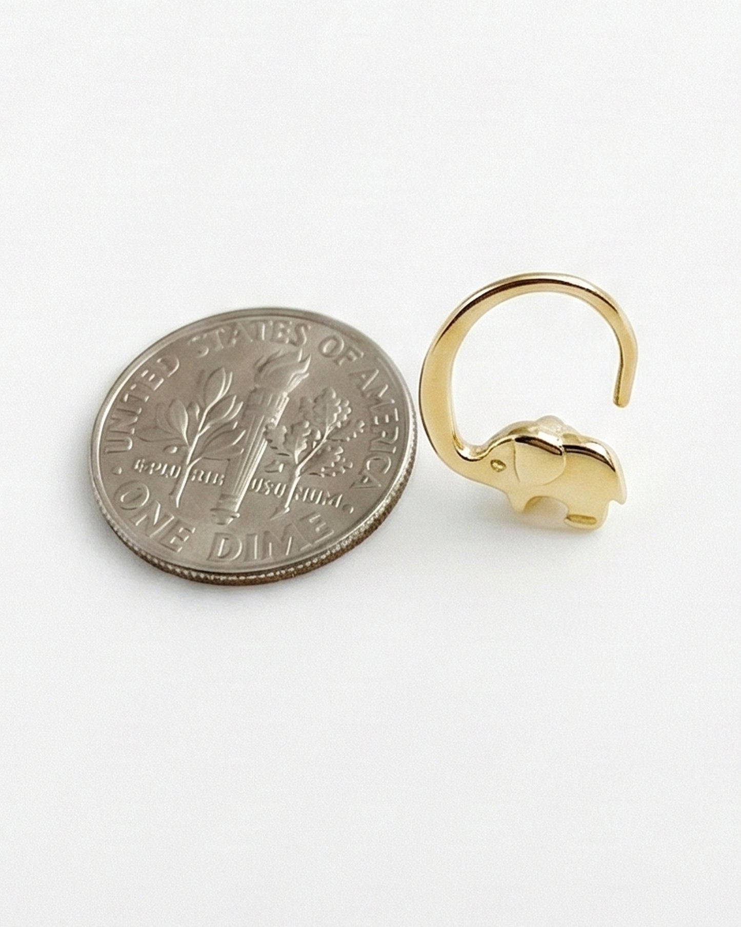 Gold elephant-shaped earring next to a U.S. dime coin on a white background